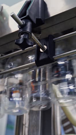 empty plastic bottles hanging from a conveyor line. bottle production line. view from below on plastic bottles for liquid in modern milk plant. vertical video