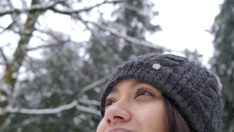 Retrato-De-Una-Joven-Y-Hermosa-Niña-Sonriente-Feliz-Con-Un-Gorro-De-Punto-En-El-Parque-Con-árboles-Cubiertos-De-Nieve