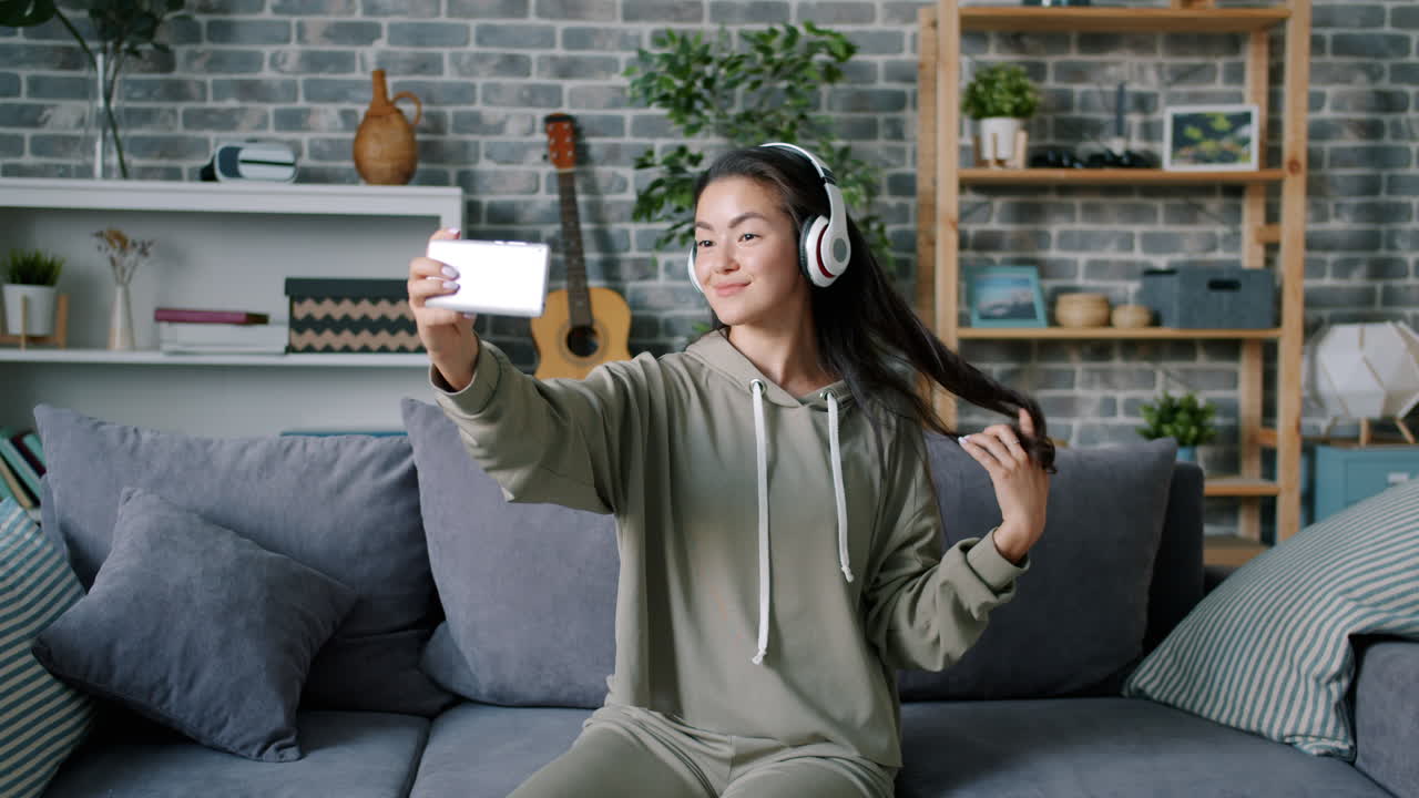 Woman taking a selfie on a couch with headphones on