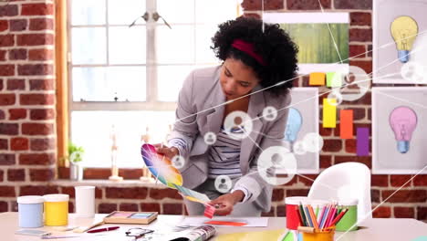 Animation of network of connections with icons over biracial businesswoman checking project
