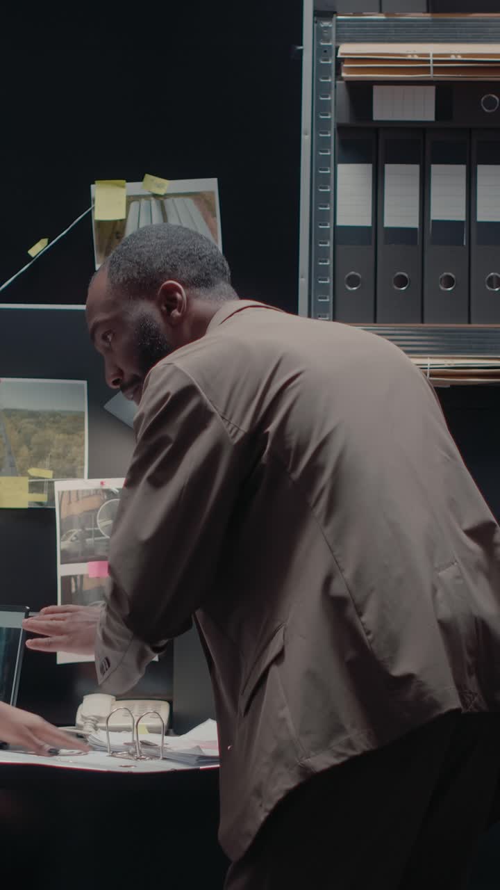 Vertical video: African american detectives looking at photos
