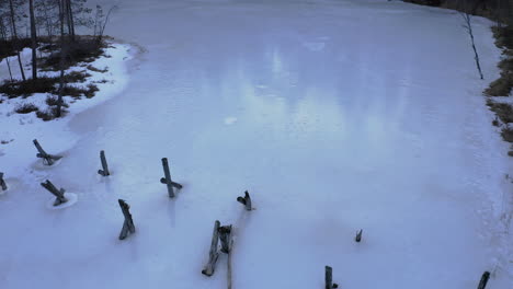 aerial drone shot of an old collapsed bridge in ice covered lake