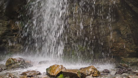 Water-jets-fall-down-into-pool-with-stones-at-wild-highland