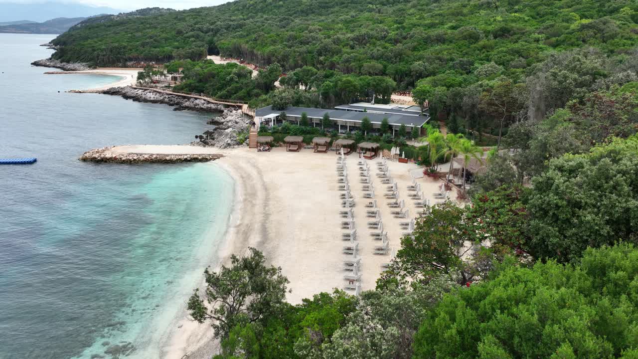 Empty Loungers on Beach with Green Forest Surroundings Aerial View