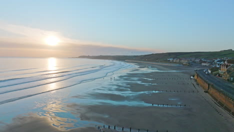 Sandsend,-Whitby,-Küste-Von-Nordyorkshire-Luftdrohnenbewegung-Vom-Meer-Zum-Meer-Und-Hundegeher