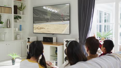 행복 한 가족 이 집 에서 함께 앉아서 tv 에서 장거리 점프 경기를 시청 하고 있다