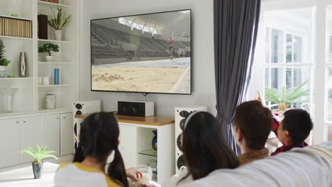 composite of happy family sitting at home together watching athletics long jump event on tv