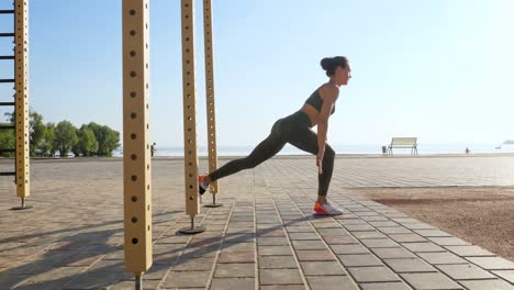 workout outdoors. suspension straps. workout with straps. athletic young woman is doing all-body resistance exercises using looped ropes trx, at the beach during sunset or sunrise. fitness training outdoors. healthy lifestyle concept. morning sport