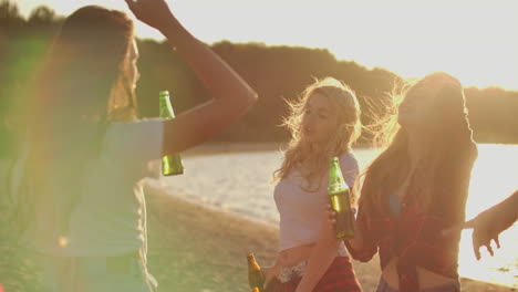 young people celebrate a birthday on the beach party with beer and have fun dancing. this is carefree summer evening at sunset.