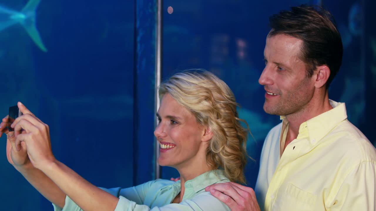 pareja feliz tomando una foto de peces