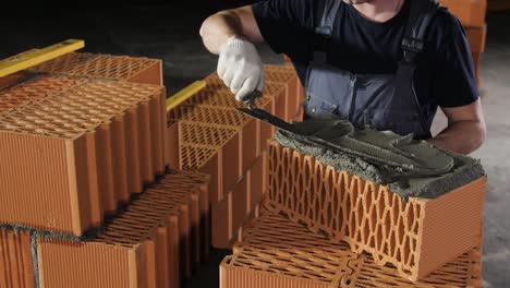 bricklayer applying mortar to brick