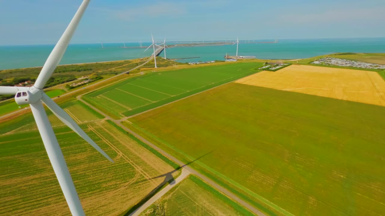 Aerial drone flight near spinning blades on modern wind turbine in green field