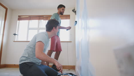 two men decorating room in new home painting wall together