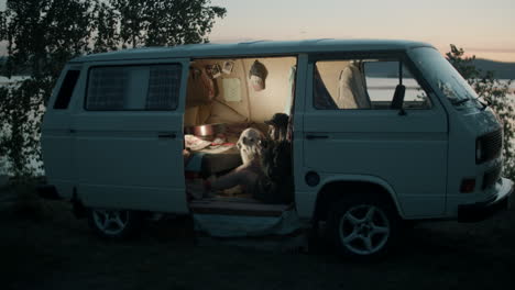 woman and dog sitting in camper van in evening