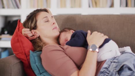 Video-Einer-Müden-Kaukasischen-Mutter,-Die-Mit-Ihrem-Neugeborenen-Auf-Dem-Sofa-Schläft
