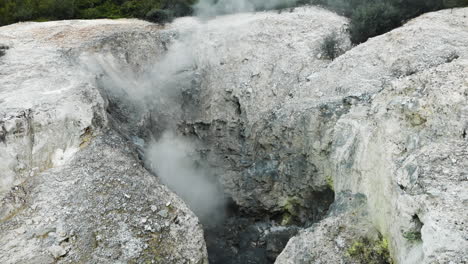 tilt up shot of fumes rising up between rocks at wai-o-tapu national park - boiling water pools between rock formation