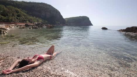 señora flaca en sus bikinis rojos en la costa de montenegro en los días soleados de verano