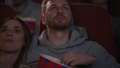 close up of young people faces watching movie at cinema theater