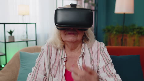 Senior-woman-using-virtual-reality-VR-app-headset-helmet-to-play-simulation-3D-360-video-game-online