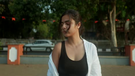 Young-Indian-woman-standing-on-a-sidewalk-in-front-of-a-busy-riad-in-India