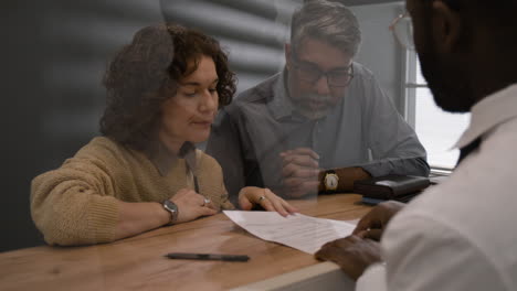 Couple Signing Documents With Doctor