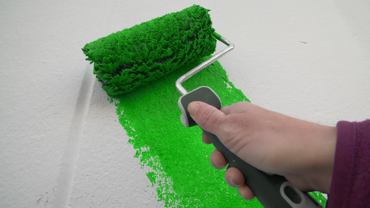movimiento lento de una mano pintando una pared blanca de color verde brillante con un pintor de rodillos