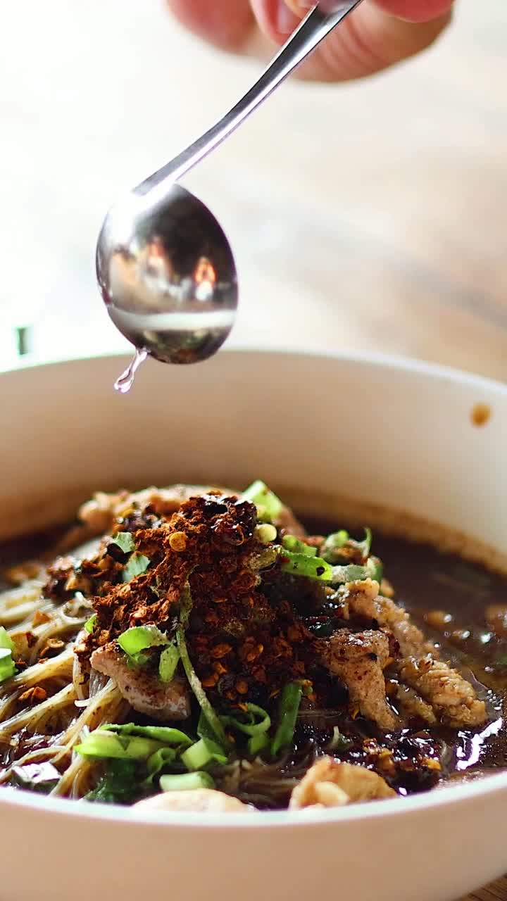 añadiendo especias a un plato de sopa de fideos