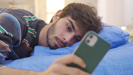 Young-man-playing-on-the-phone-falls-asleep-in-bed.