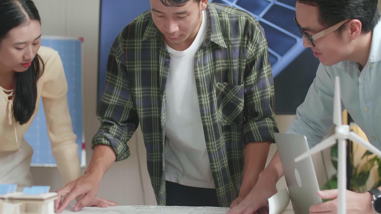 태양 전지 패널 집 모형과 함께 아시아 엔지니어 그룹의 클로즈업은 청사진을 열고 사무실에서 작업에 대해 논의합니다.