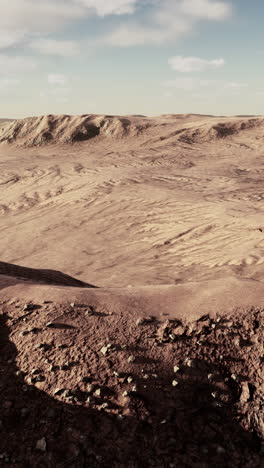 un paisaje desolado del desierto con dunas de arena roja y colinas que se extienden hasta el horizonte bajo un cielo nublado