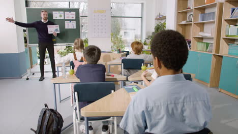 profesor enseña a un grupo de estudiantes multiétnicos las palabras 'pequeño' y 'grande' en el aula de inglés