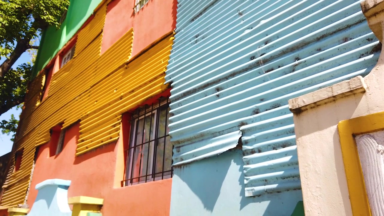 Pan Left Tilt Down Over Caminito Colorful Corrugated Facades in Orange Yellow and Light Blue Capturing the Raw Handmade Identity of La Boca Buenos Aires