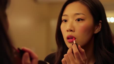 a woman perfectly applying lipstick in front of a mirror: capturing the elegance of beauty and self-confidence in a glamorous setting