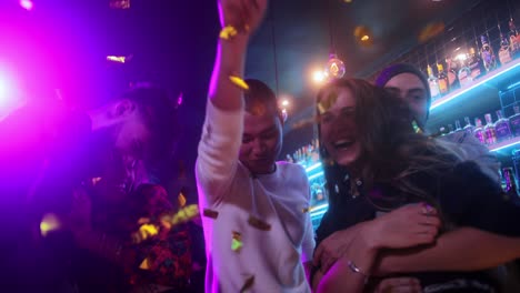 grupo multiétnico de amigos bailando lanzando confeti dentro de un bar de moda