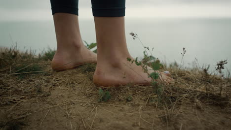 barefoot unknown woman standing beach hill close up. bare legs placed hilltop.