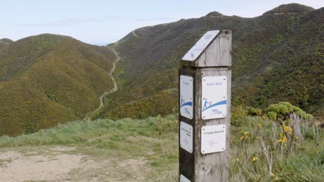 a sign showing directions on a walking track with hills in the background