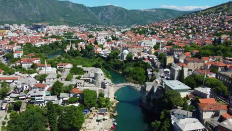 aerial drone footage of mostar, bosnia and herzegovina, showcasing the iconic old bridge (stari most), winding turquoise neretva river, and historic ottoman-style architecture
