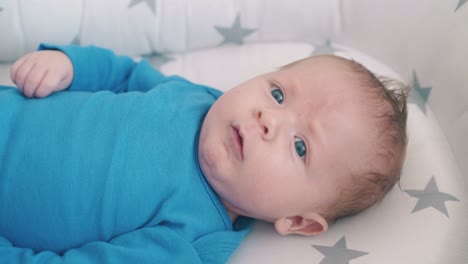 little baby kicks legs lying in soft textile cocoon in crib