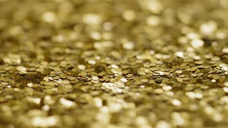 Slow-pan-across-bright-gold-sequins-and-glitter,-macro-shallow-focus