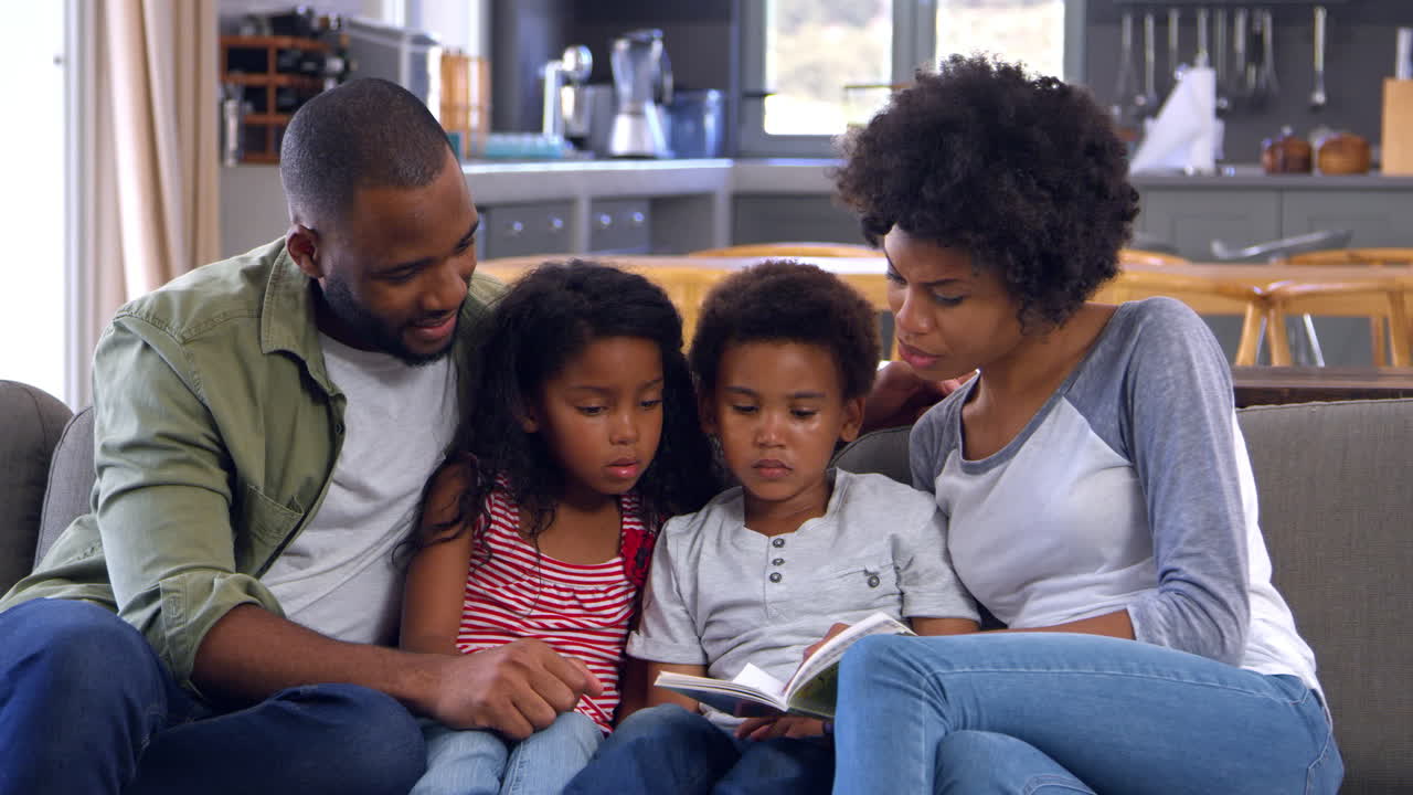 Famiglia seduta sul divano in salotto che legge un libro insieme
