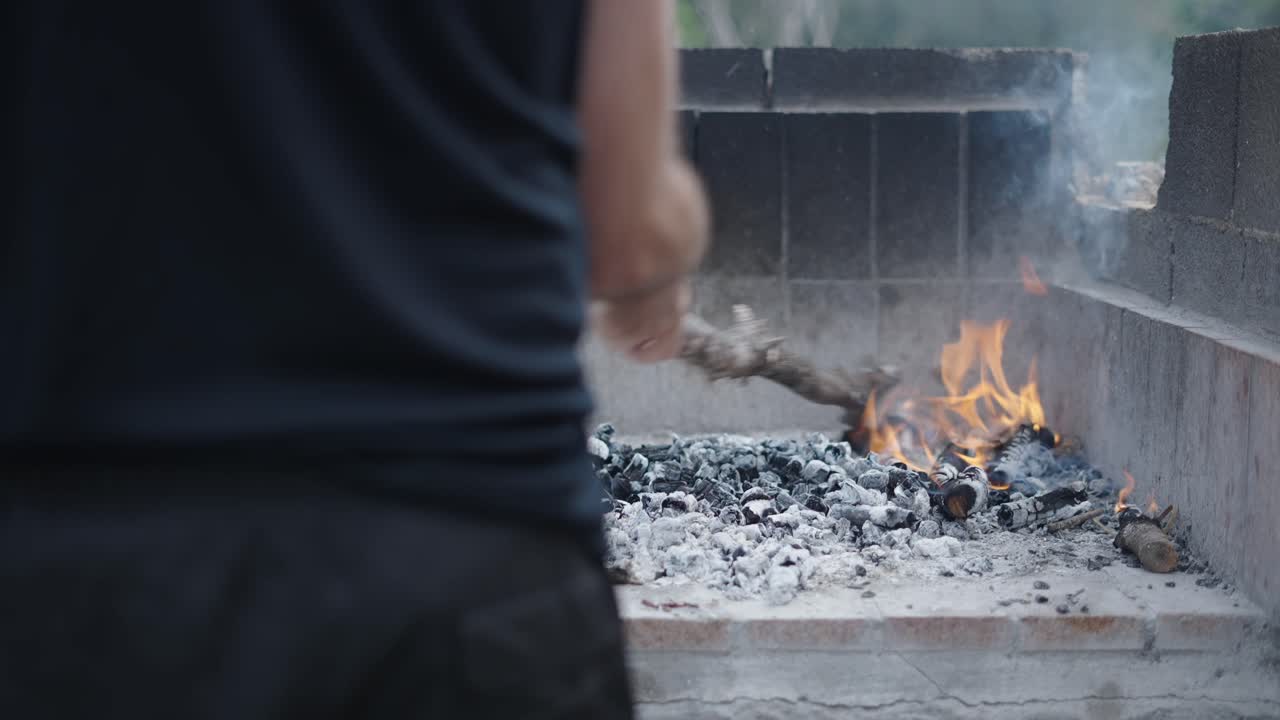 Preparing a BBQ grill with burning wood and embers