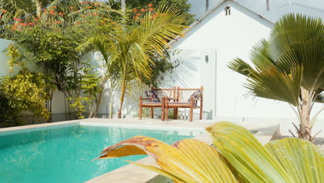 two inviting chairs by a turquoise pool in a private spa, bathed in sunlight amidst tropical surroundings