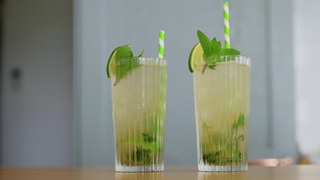 Hand-Putting-Glass-of-Mojito-Cocktail-on-Table.drinks-and-people-concept--hand-of-woman-putting-glass-of-lime-mojito-cocktail-on-table-at-home