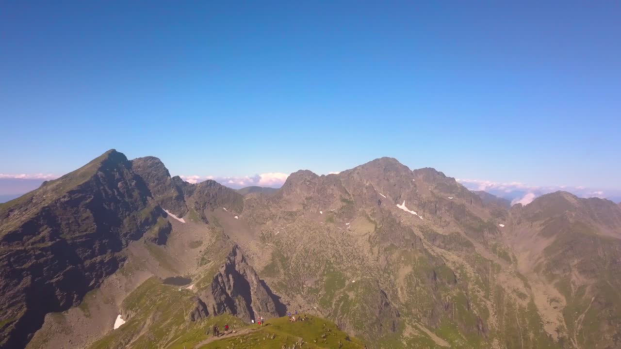 사람들은 네고이우 피크 근처 루마니아 외딴 지역의 깊은 협곡, 가파른 절벽, 울퉁불퉁한 풍경의 놀라운 전망을 바라보며 산봉우리 위에 서 있습니다.