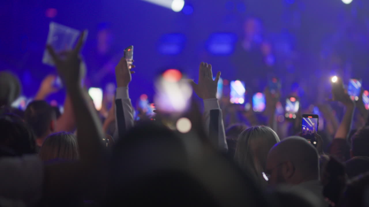 Folla a un concerto con mani alzate e cellulari