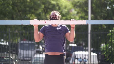Fit-bearded-man-trains-doing-push-ups-on-a-soccer-goal-on-a-public-park