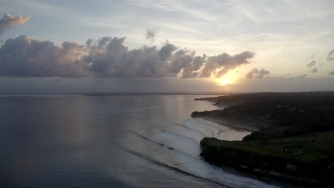 dramatic sunset at balangan beach in bali indonesia with kuta golf course over the cliffs right, aerial hover shot