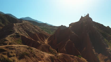 Revealing-drone-shot-of-hiker-on-canyon-ridge-at-Fairy-Tale-Canyon-near-Issyk-Kul-Lake-in-Karakol,-Kyrgyzstan