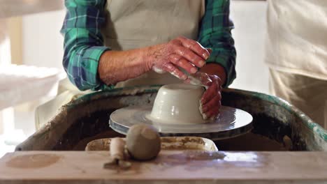 Mid-section-of-male-potter-assisting-female-potter