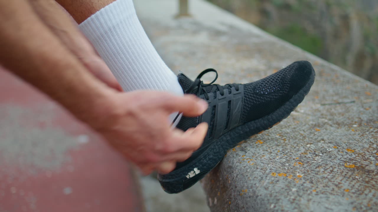 atleta atando zapatillas de zapatos al aire libre de cerca. las manos preparan zapatos de entrenamiento.
